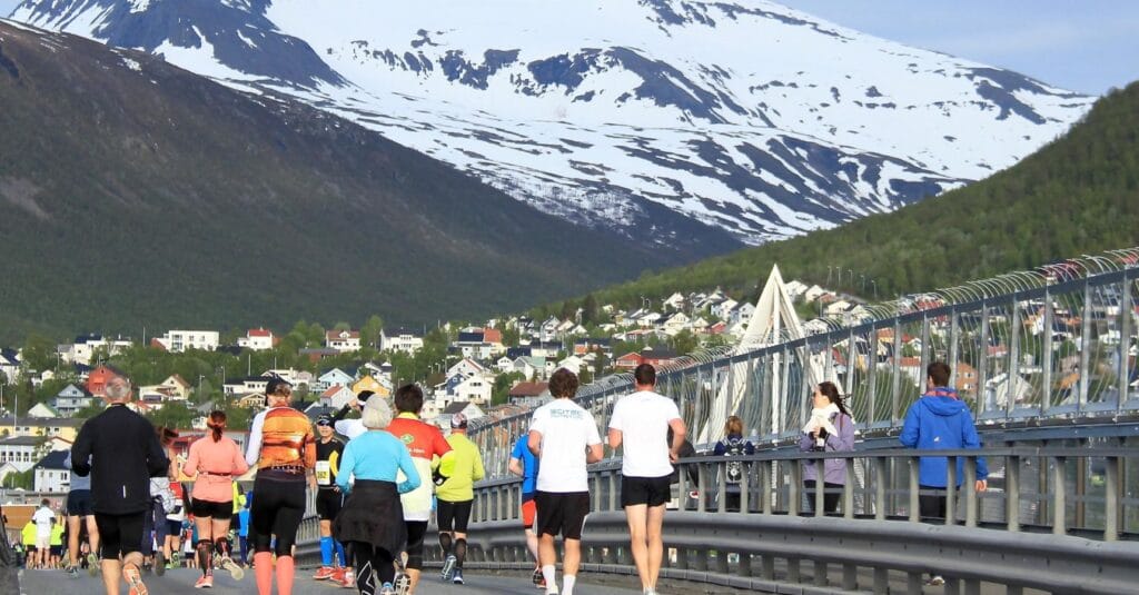 Runners head over a bridge with mountains in the background